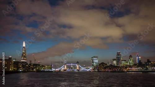 Timelapse of the London skyline at night with The Shard, Tower Bridge and the new skyscrapers of The City including 122 Leadenhall Street, The Gherkin and the Heron Tower. Boats on river Thames. photo