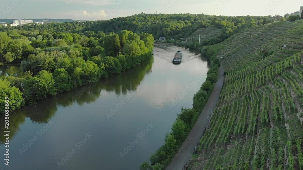 Cargo Ship on a river at sundown in between vineyards and forest Cargo Ship on a river at sundown in between vineyards and forest
