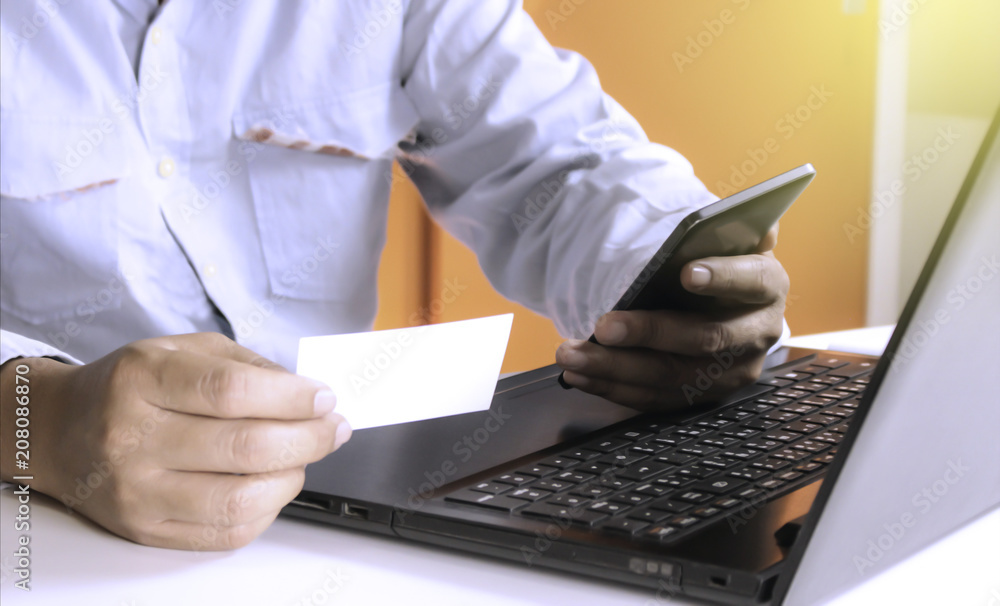 Hands using laptop and check business cards for calling online shopping with daytime soft light shining high contrast Hands using laptop and check business cards for calling online shopping with daytime soft light shining high contrast