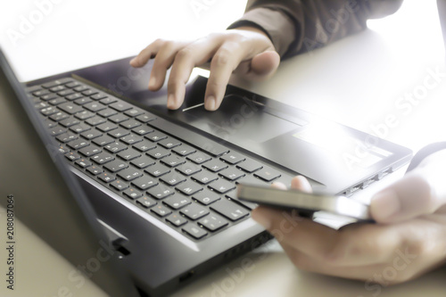 Hands using laptop and smartphone for online shopping with daytime soft light shining high contrast