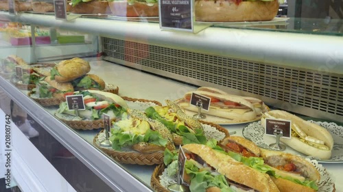 Baguette sandwiches layout behind glass chowcase at food point on a street of Paris