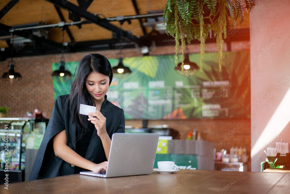 Young woman holding credit card and using laptop computer. Online shopping concept Young woman holding credit card and using laptop computer. Online shopping concept