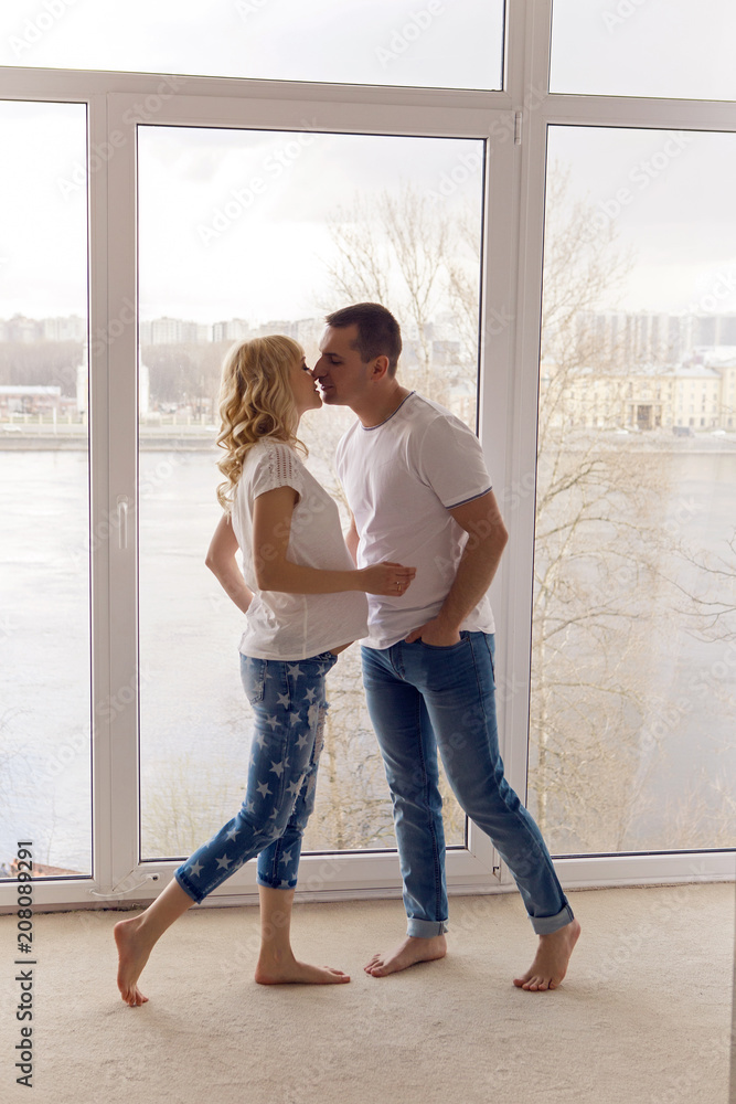 pregnant girl standing with her husband next to the window pregnant girl standing with her husband next to the window