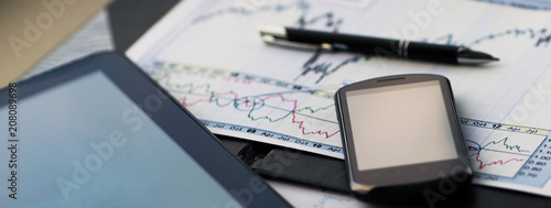 Close up image of tablet with a phone and a schedule with pen at workplace