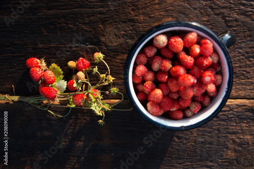 fresh wild strawberries in a Cup in the shape of a heart, symbol of love. Wooden background. The view from the top photo