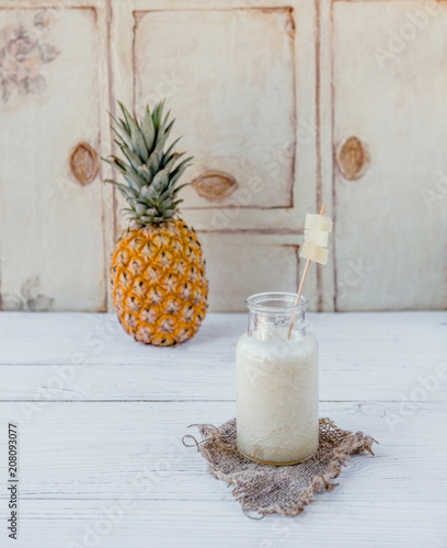 Delicious detox smoothie with pineapple on white wooden board