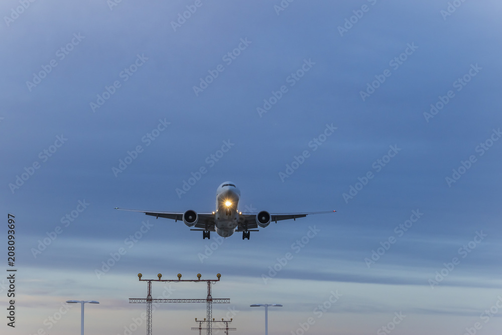 A jetliner  with  headlights on approaches for landing over visual approach slope indicator in a low light
