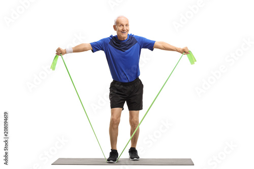 Senior standing on an exercise mat and working out with a rubber band