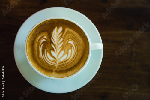 top view of Coffee cup with latte art on wooden table . Selective focus white cup.color vintage style.
