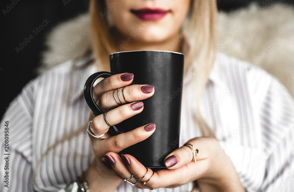 Female hands holding a white cup of tea, burgundy manicure, the girl is dressed in a shirt Female hands holding a white cup of tea, burgundy manicure, the girl is dressed in a shirt