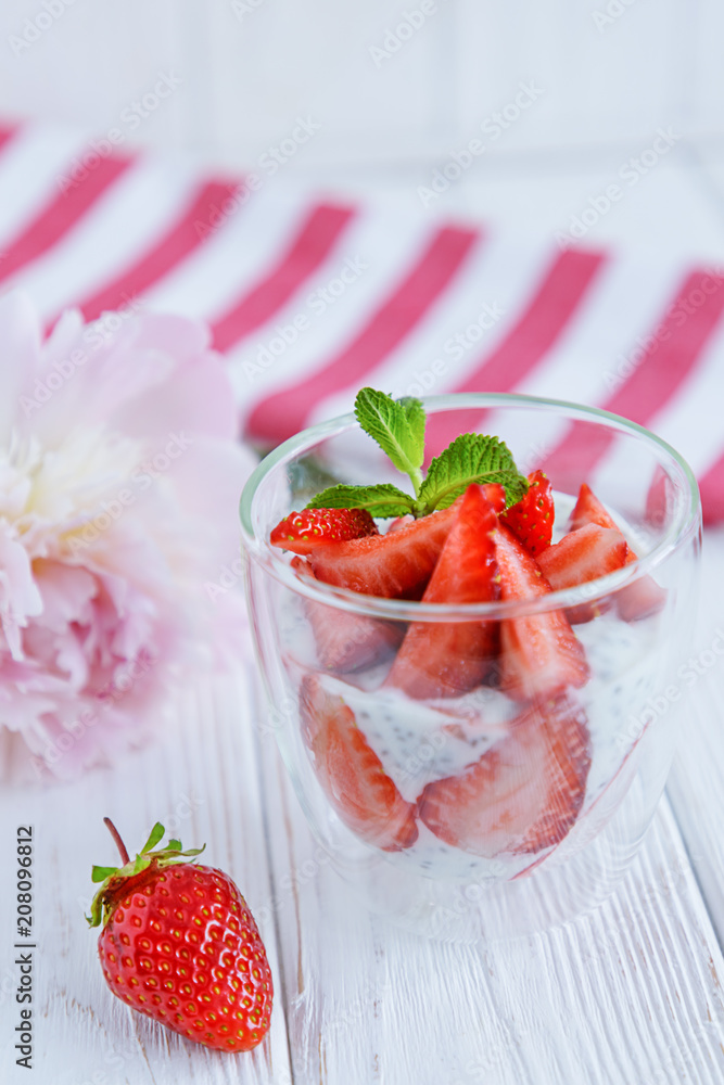 Chia pudding with fresh strawberries and mint in glass on striped background. Concept of healthy breakfast Chia pudding with fresh strawberries and mint in glass on striped background. Concept of healthy breakfast