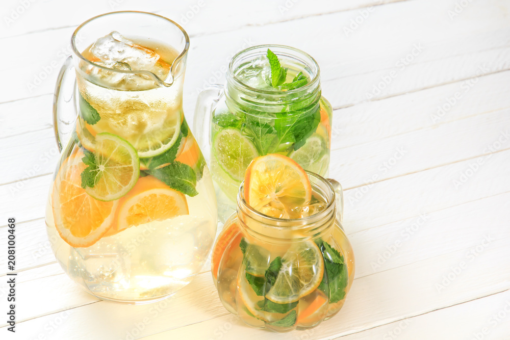 Glass jug and glasses with fresh lemonade stand on white wooden rustic boards in bright light. Copy space Glass jug and glasses with fresh lemonade stand on white wooden rustic boards in bright light. Copy space