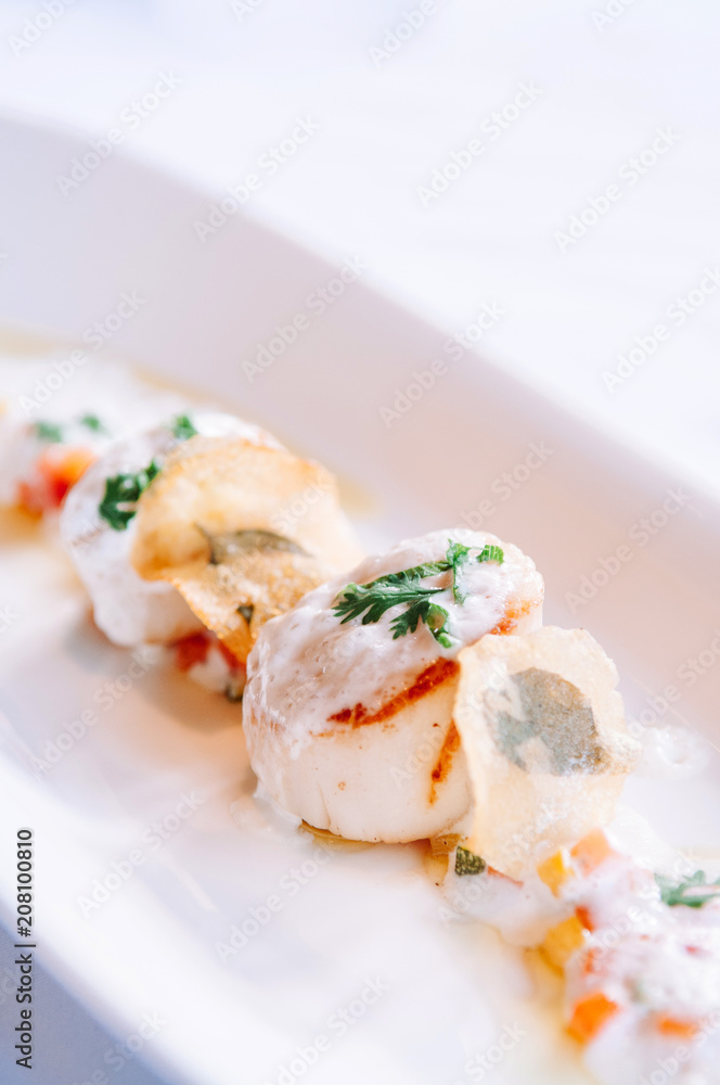 Grilled scallops on a white plate with creamy foam sauce, fine dinning cuisine Grilled scallops on a white plate with creamy foam sauce, fine dinning cuisine