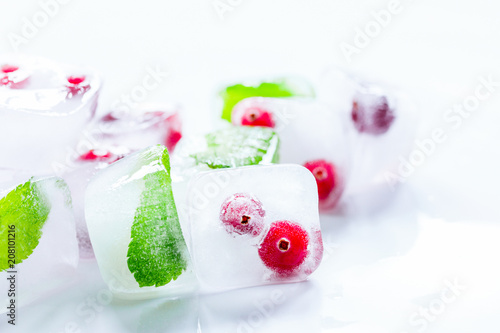 Ice cubes with berries and mint for summer drink on white backgr