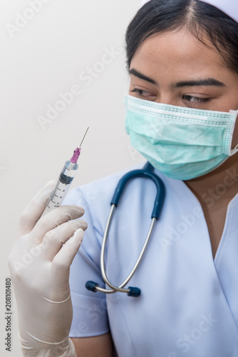 Nurse holding medical syringe with needle in ampule getting ready for patient injection.