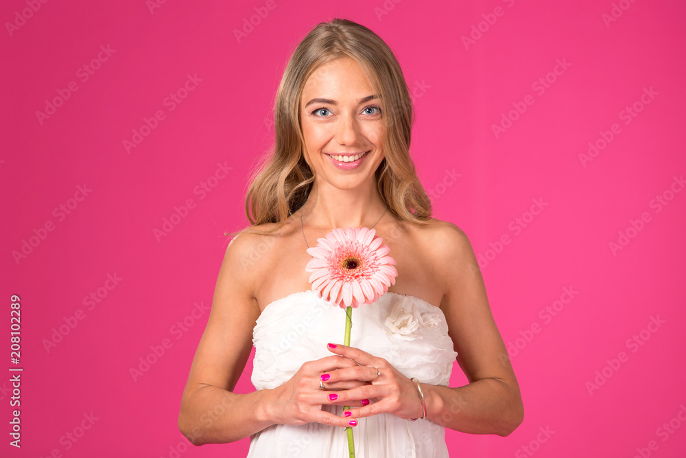 Beautiful woman with a gerbera flower on a pink background. Beautiful woman with a gerbera flower on a pink background.