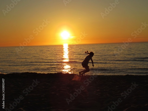 Girls Jumping at Sand Beach Seaside during Sunset with Clouds