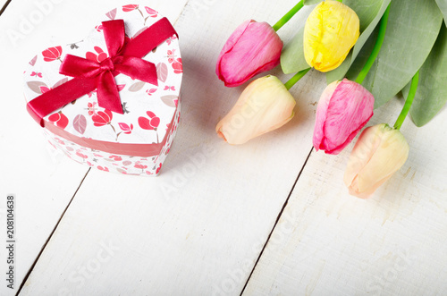 High angle shot of pink rosy and yellow Spring tulip flowers and gift box on white wooden table