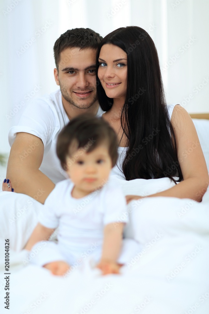 Cute little boy with parents on the bed