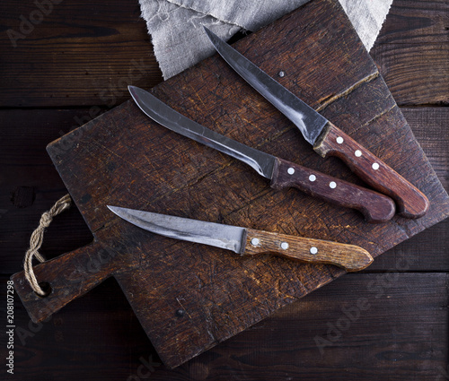 three old kitchen knives on a brown wooden cutting board