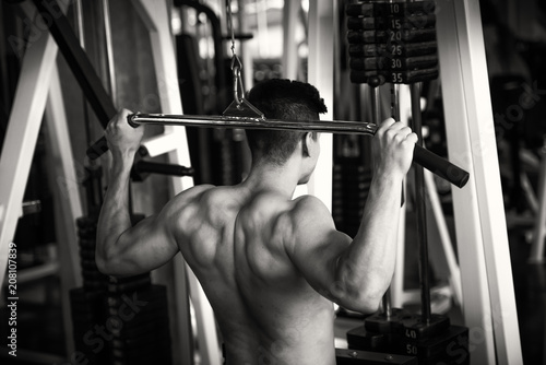 Portrait of young man using weight lifting equipment , bodybuilder concept.
