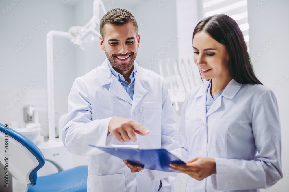 dentist and assistant looking at clipboard dentist and assistant looking at clipboard