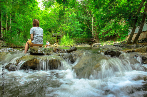 woman sitting together by the creek and looking away at a view.