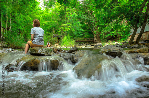 woman sitting together by the creek and looking away at a view.