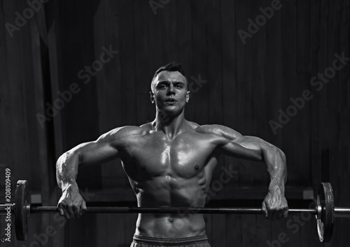 Portrait of strong muscular man working out with barbell, black and white image © Denys Kurbatov