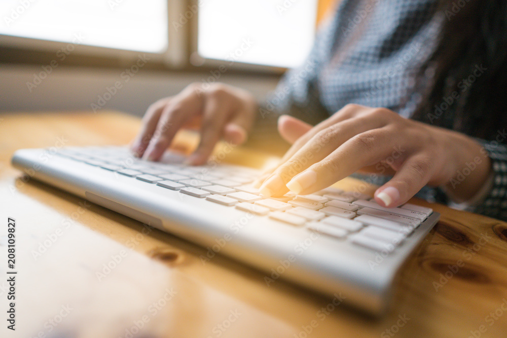 Close-up image of female hands typing text on a wireless keyboard. Business woman working at the office. On wooden table. Copy space Close-up image of female hands typing text on a wireless keyboard. Business woman working at the office. On wooden table. Copy space
