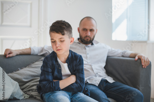 Cuadro en lienzo A sad and resentful boy and an angry father in the background.