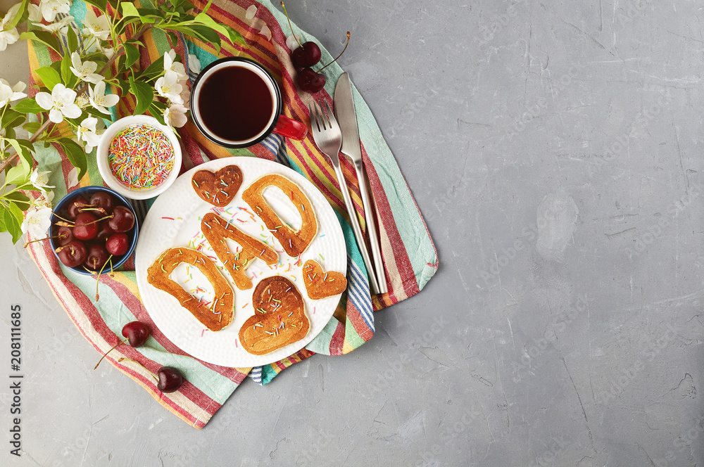 Special Father's Day breakfast. Alphabet Pancakes with sprinkles, cherries and cup of tea on a gray concrete background