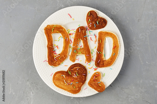 Special Father's Day breakfast. Alphabet Pancakes with sprinkles on white round plate. Top view, close up