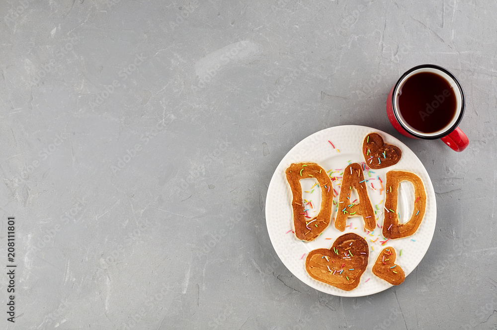 Special Father's Day breakfast. Alphabet Pancakes with sprinkles on white round plate and cup of tea