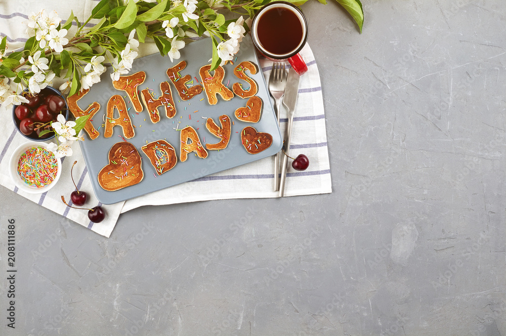 Special Father's Day breakfast. Alphabet Pancakes with sprinkles, cherries and cup of tea on a gray concrete background