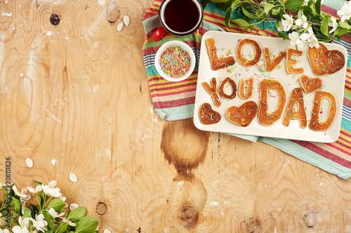 Special Father's Day breakfast. Alphabet Pancakes with sprinkles, cherries and cup of tea on wooden background