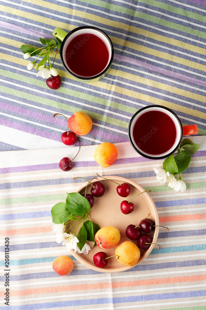 Summer still life with berry tea, ripe apricots, juicy cherries and apple blossoms