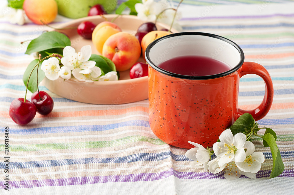 Summer still life with berry tea, ripe apricots, juicy cherries and apple blossoms