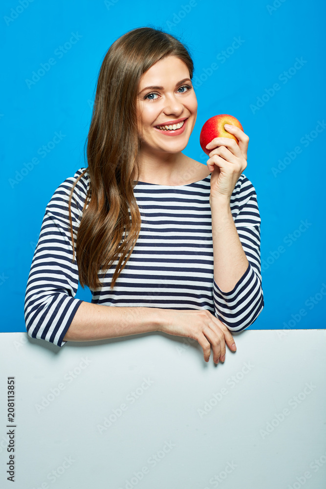 Smiling woman wearing striped shirt holding red apple with white Smiling woman wearing striped shirt holding red apple with white