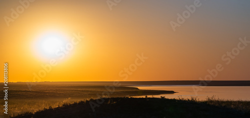 Beautiful sunset over the lake and field