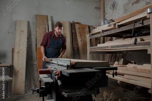 Master carpenter saws the board on machine in workshop
