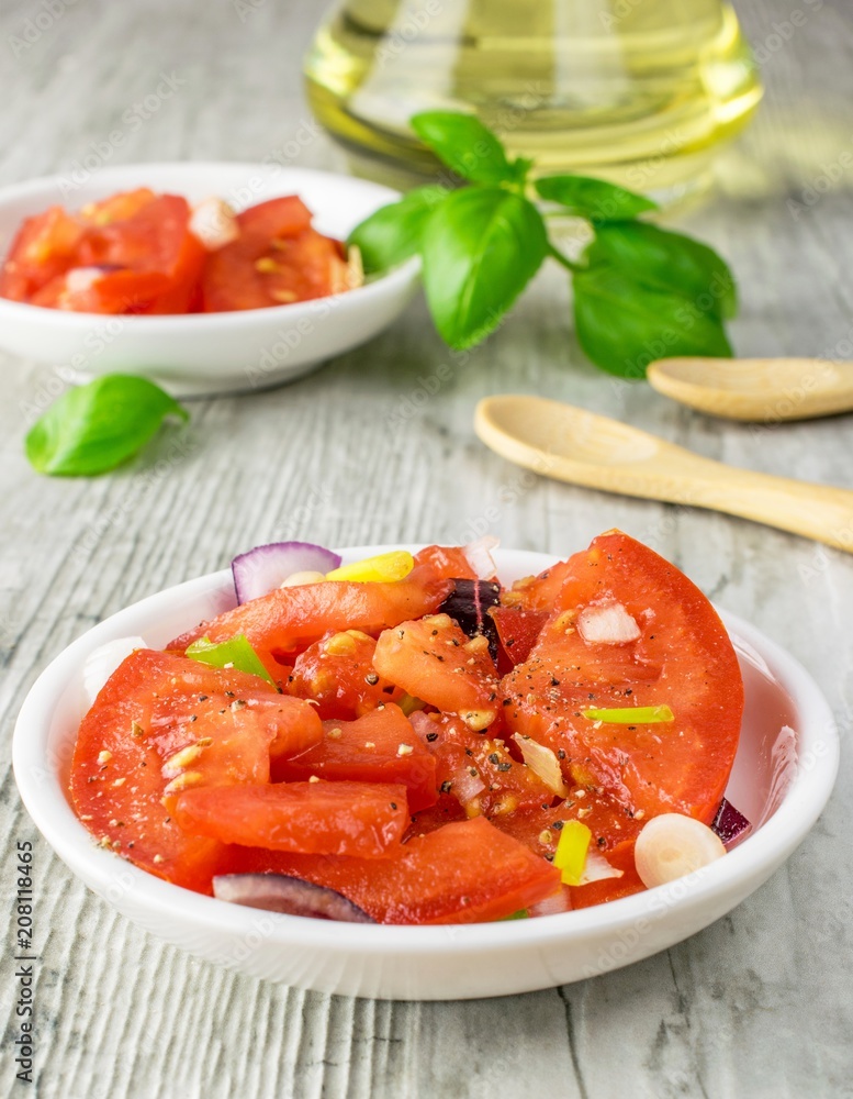 A close up of a fresh tomato and onion salad on a rustic wooden kitchen table A close up of a fresh tomato and onion salad on a rustic wooden kitchen table