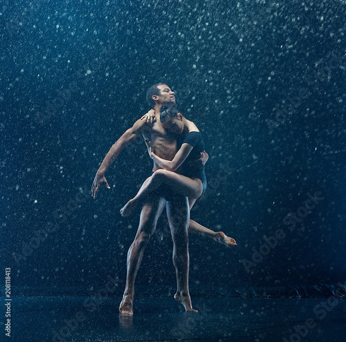 Young couple of ballet dancers dancing unde rwater drops