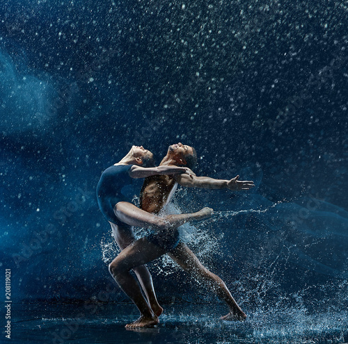 Young couple of ballet dancers dancing unde rwater drops