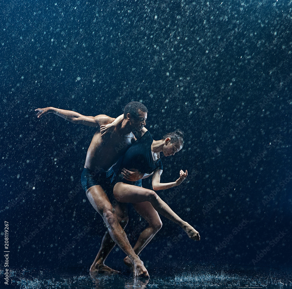 Young couple of ballet dancers dancing unde rwater drops