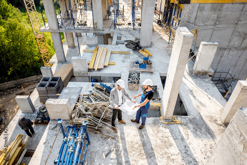 Top view on the construction site of residential buildings during the construction process with two workers standing with drawings