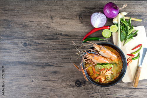 Close up Asian Spicy soup with shrimp in bowl , famous Thai food cuisineม Tom Yum Goong Spicy Sour Soup on wooden table top view