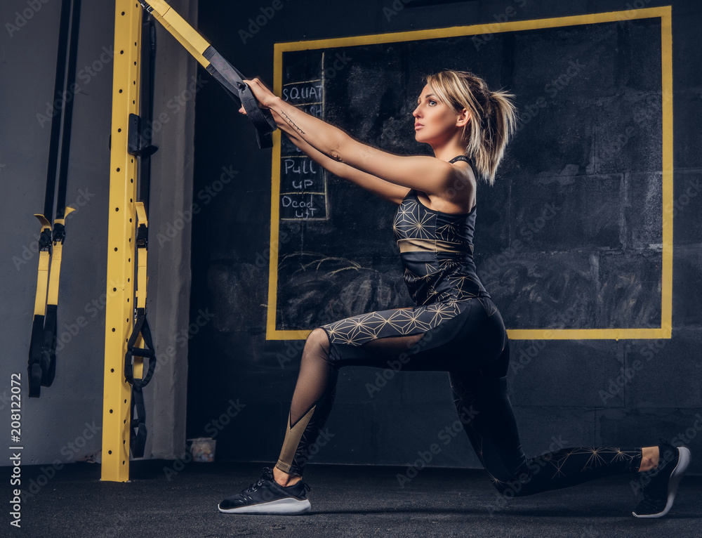 Sexy blonde woman in sportswear doing exercise with TRX system at gym.  Stock Photo | Adobe Stock