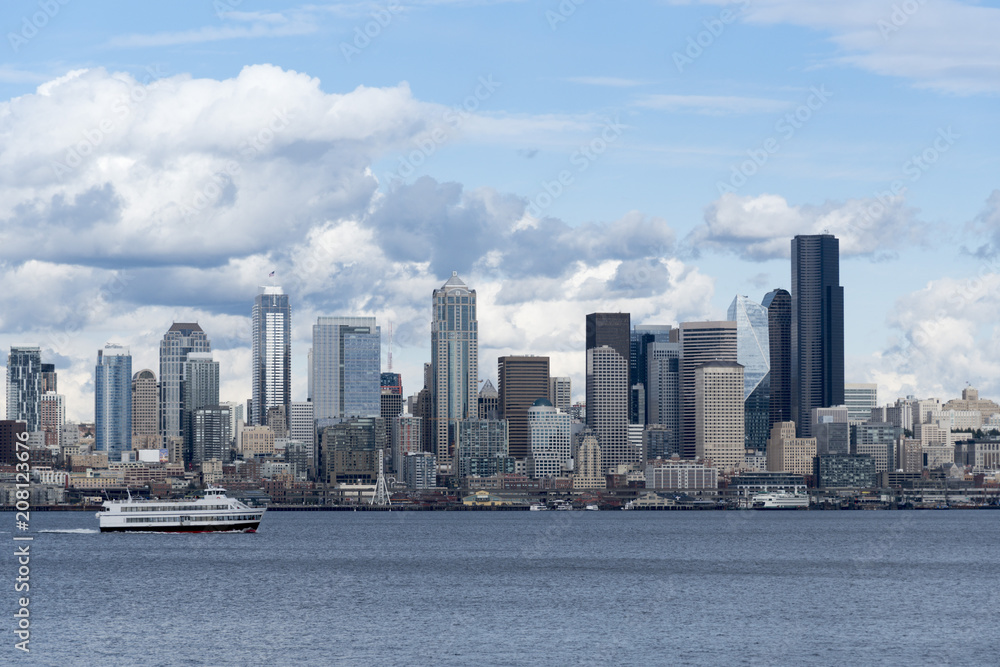 Seattle skyline with boat on Elliott bay under afternoon partly cloudy clouds