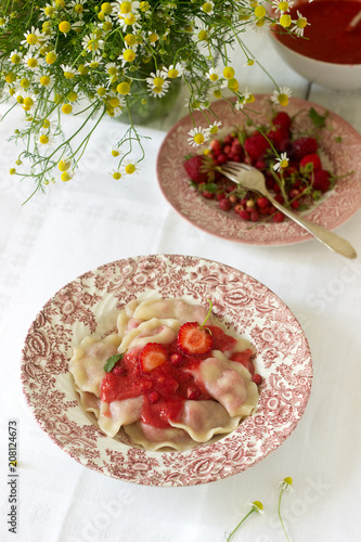 A hearty homemade breakfast or lunch - dumpling or vareniki with strawberries and strawberry sauce. Rustic style.
